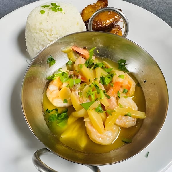 Cuban-style shrimp scampi in a metal bowl with white rice and fried plantains on a white plate.